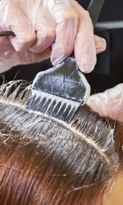 Hier wird der Ansatz einer Kundin mit einem Pinsel gefärbt beim Coiffure Piazza.